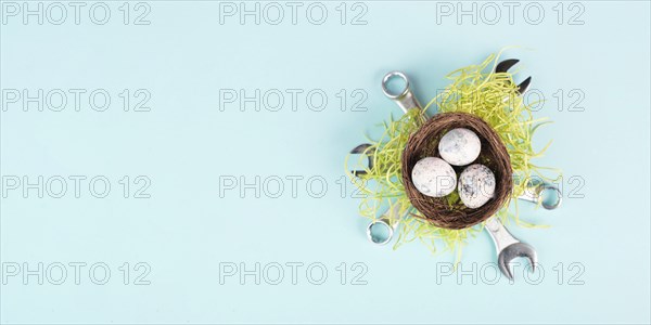 Easter eggs in a bird nest, wrenches and green grass, holiday greeting card with repair tools, spring season