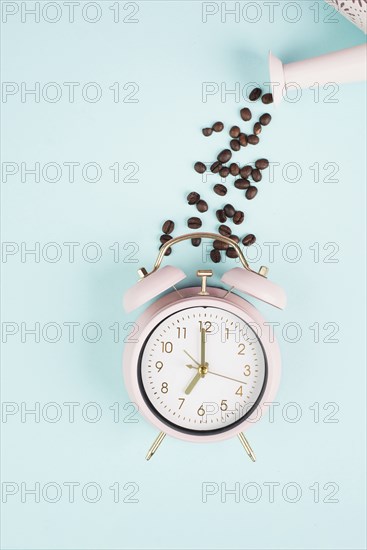 Wake up in the morning, time for breakfast, coffee break, alarm clock with roasted beans pouring from a watering can