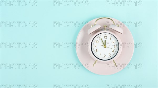 Alarm clock on a plate in old retro style, pastel color, time for a break, having lunch