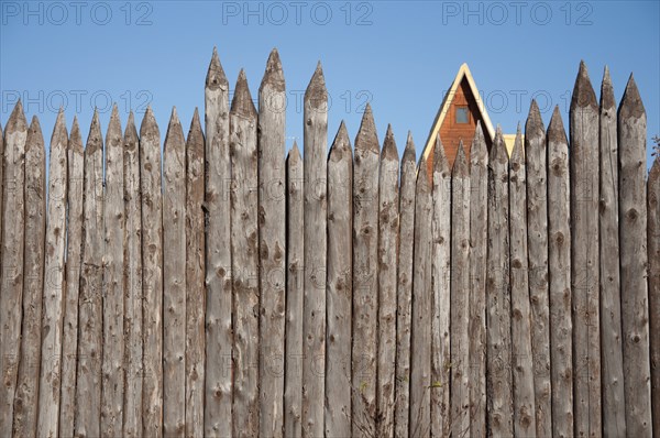 The wooden fence of sharpened logs timber