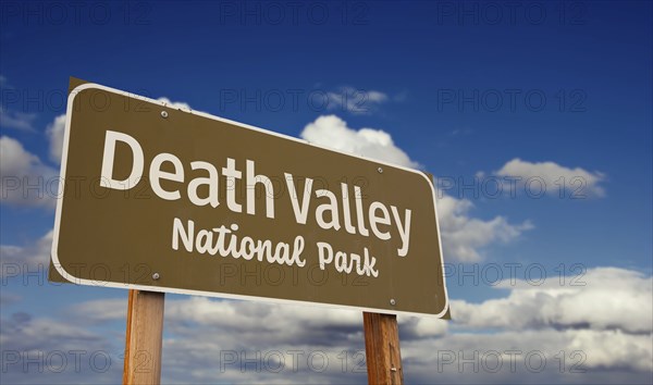 Death valley national park (california, nevada) road sign against blue sky and clouds