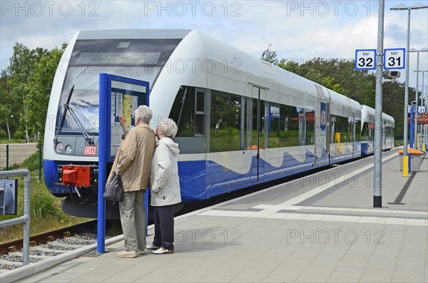 Two people look at the tour list at the local trains that serving Stralsund in Germany and Swinoujscie in Poland at platform in Swinoujscie, Swinemünde, West Pomerania, Poland, Europe