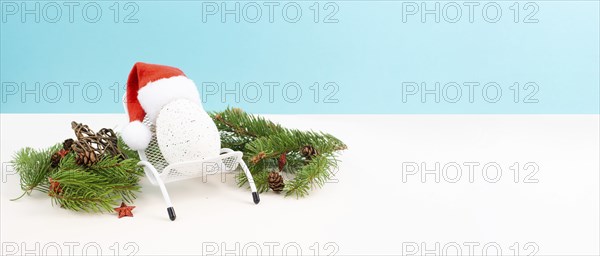 Santa Claus with a red hat sitting in a lounge chair, holiday by the sea, taking a vacation, christmas decoration with fir, cones and stars