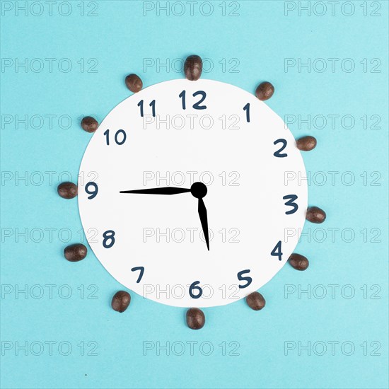 Alarm clock with numbers and coffee beans, wake up in the morning, having a deadline, time for a break, minimalistic concept, blue background