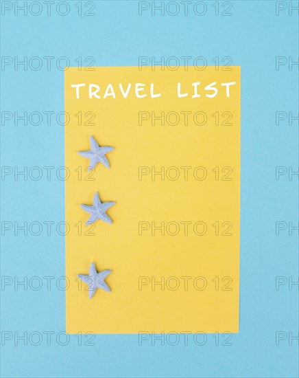 Travel list is standing on the yellow colored paper, sea stars, holiday plan and destination, vacation and lifestyle concept