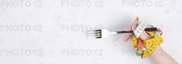 One single pea on a fork, hand with tape measure and fork, diet and loosing weight concept, healthy lifestyle