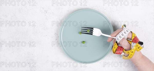 One single pea on a plate, hand with tape measure and fork, diet and loosing weight concept, healthy lifestyle