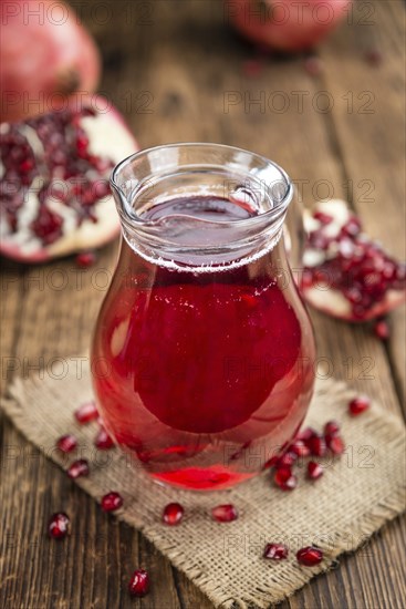 Pomegranate juice as high detailed close-up shot on a vintage wooden table (selective focus)