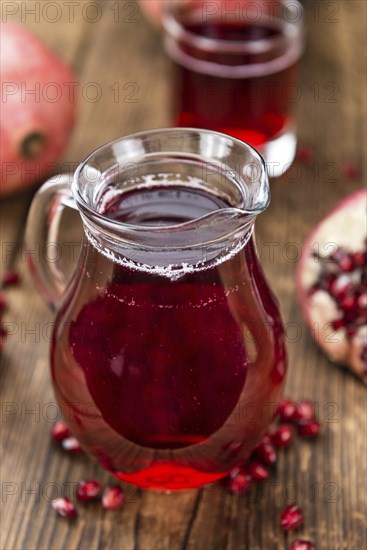 Pomegranate juice as high detailed close-up shot on a vintage wooden table (selective focus)