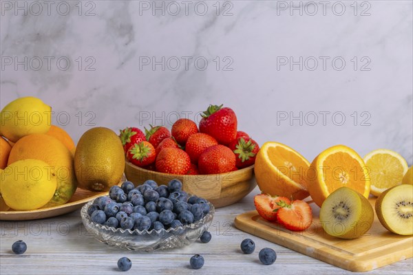 Harmonious still life of various fruits, strawberries, lemons, oranges, kiwis and blueberries, partly sliced