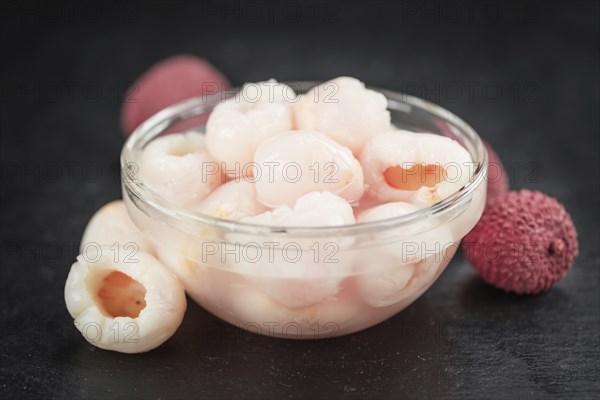 Portion of Lychees (preserved) on a rustic slate slab (selective focus, close-up shot)