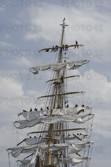 New London, Connecticut, USA, July 2012: Crew members high up in the rigging furl the sails on the US Coast Guard cutter Eagle when it arrives at Fort Trumbull, New London, Connecticut at the conclusion of the Parade of Sail during Operation Sail 2012 aka OpSail 2012. New London is the Eagle's homeport. Originally a German vessel, the ship was built in 1936 by the Blohm and Voss Shipyard in Hamburg, Germany. The square rigger is a training vessel for US Coast Guard cadets. While underway, the Eagle's crew must handle more than 22, 000 square feet of sail and five miles of rigging, North America