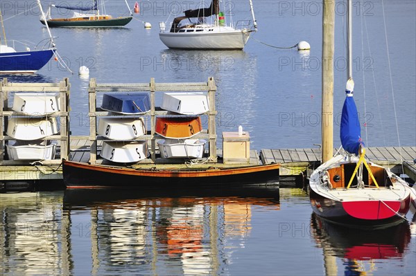 Rockland Harbor Maine USA with colorful sailboats, dinghies and rowboats moored along the dock and colorful reflections in the water