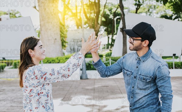 Girl and a guy shaking hands on the street. Two young smiling friends greeting in the street. Concept of man and woman shaking hands on the street