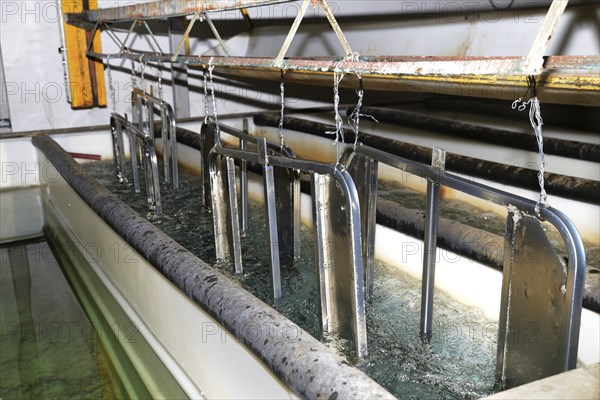 A set of zinc-plated gates for an abattoir receive a rinse in clean water as part of the electroplating process. Each gate is wired to the frame to create an electric circuit