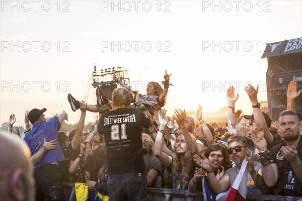 Crowdsurfers in front of the evening sun at the Wacken Open Air in Wacken. The traditional metal festival takes place from 31 July to 3 August 2024