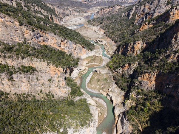 An aerial view of a deep gorge with a meandering river surrounded by steep cliffs and lush vegetation, aerial view, Congost de Mont-rebei gorge, Noguera Ribagorçana Mont-rebei Natural Park, Montsec mountain range, Noguera Ribagorçana river, Lleida province, Catalonia, Aragon, Spain, Europe