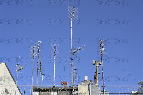 Various antennas on the roof of a residential apartment building, installation for communication and media such as tv, internet, smartphone and radio, blue sky, copy space, selected focus