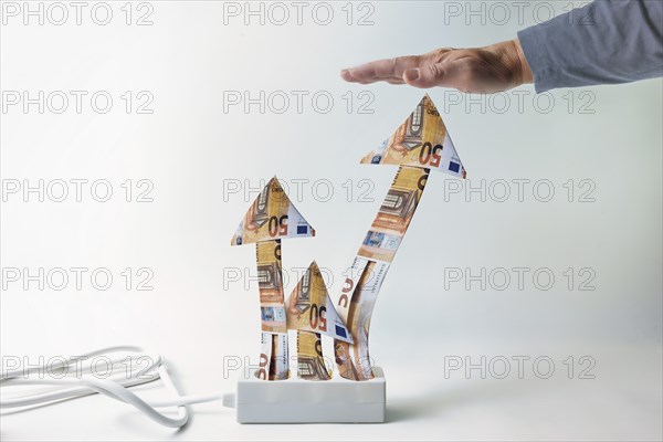 Energy price limit, or Strompreisbremse, power strip with rising arrows of money, hand from above is limiting price growth during economic crisis, light gray background, copy space, selected focus