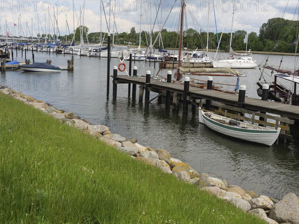 Boats at the dock in a quiet harbour surrounded by grass and a green waterfront, Kappeln, Schleswig-Holstein, Germany, Europe