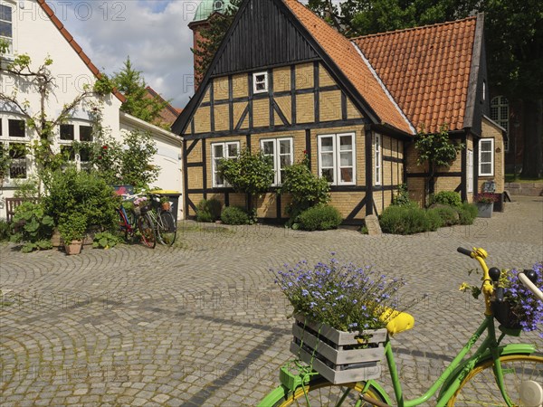 Charming village square with half-timbered house, colourful flowers and parked bicycles under a sunny sky, Kappeln, Schleswig-Holstein, Germany, Europe