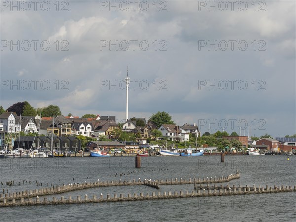 A city view with a television tower, buildings and boats on the waterfront under a partly cloudy sky, Kappeln, Schleswig-Holstein, Germany, Europe