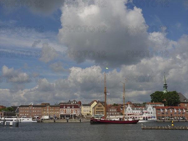 View of a harbour with historic buildings and a sailing ship under a partly cloudy sky, Kappeln, Schleswig-Holstein, Germany, Europe