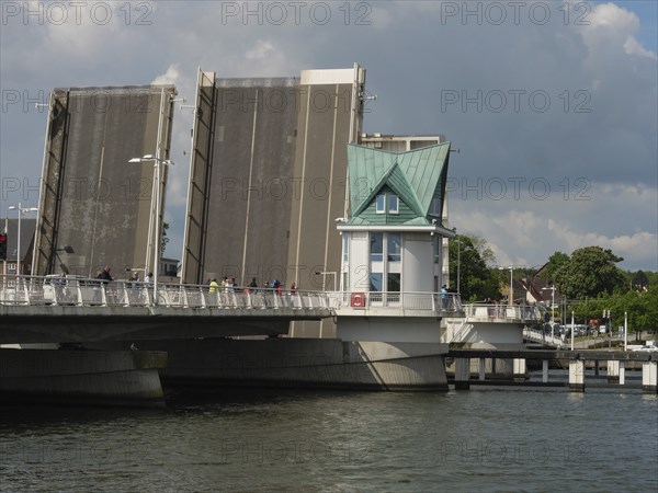 An open bridge next to a small watchtower over a river under a cloudy sky in a town, Kappeln, Schleswig-Holstein, Germany, Europe