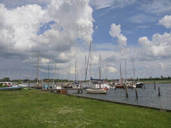 Tranquillity at the harbour where sailboats bob in the water under a cloudy sky, Arnis, Schleswig-Holstein, Germany, Europe