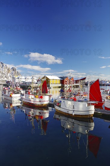 Fishing boats with red sails lying calmly on the quay, reflected in the water, surrounded by snow-capped mountains, fishing, Lofoten, Svolvaer, Nordland, Arctic, Norway, Europe