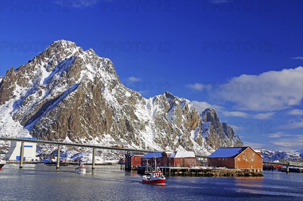 Harbour with bridge, surrounded by snowy mountains, boats in the water and sheds on the shore, Lofoten, Svolvaer, Nordland, Arctic, Norway, Europe