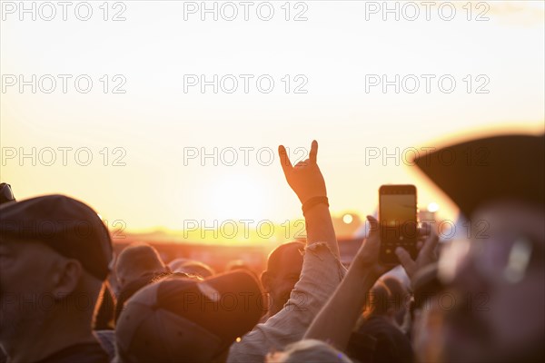 Metal greeting in front of the setting sun at the Wacken Open Air in Wacken. The traditional metal festival takes place from 31 July to 3 August 2024