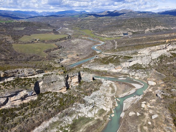 Aerial view of a stunning mountain landscape with steep rock faces and a river meandering through the valley, under a cloudy sky, aerial view, Noguera Ribagorçana River, Lleida Province, Catalonia, Aragon, Spain, Europe