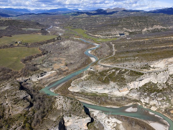 Aerial view of a picturesque landscape with a river meandering through a valley, surrounded by mountains and rocks under a cloudy sky, aerial view, Noguera Ribagorçana river, Lleida province, Catalonia, Aragon, Spain, Europe