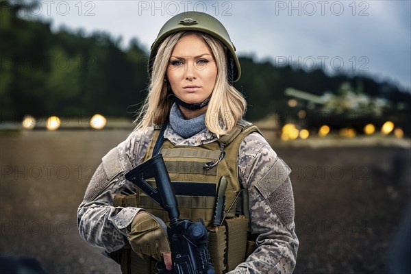 Woman in military uniform and helmet holding a gun in front of a tank on a forest road, AI generated, AI generated