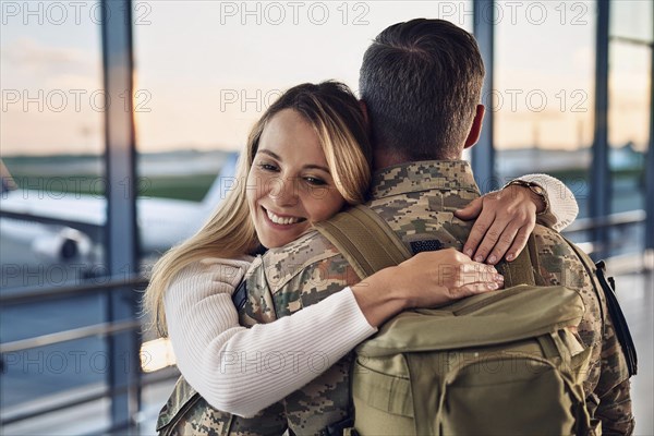 A woman hugs a soldier in an airport area at sunset, AI generated, AI generated