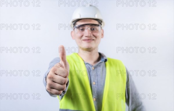 Smiling young engineer gesturing approval with thumb. Cheerful engineer giving thumbs up to the camera isolated