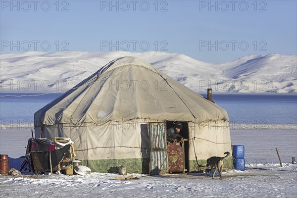 Kyrgyz man in door opening of traditional yurt in the snow along Song Kul, Song Kol lake in the Tian Shan Mountains, Naryn Province, Kyrgyzstan, Asia