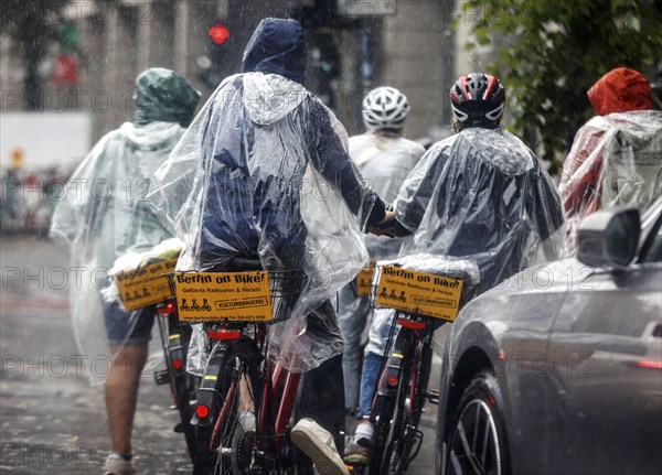 Tourists on a Berlin On Bike bike tour with rain capes in heavy rainfall, Berlin, 23 06 2023