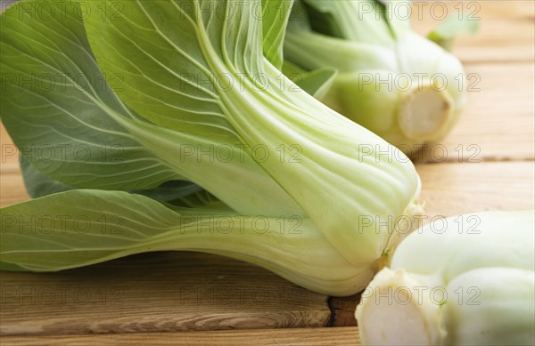 Fresh green bok choy or pac choi chinese cabbage on a brown wooden background. Side view, close up