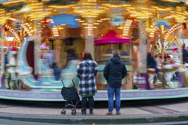 Pre-Christmas season, Christmas market at Kennedyplatz in the city centre of Essen, carousel, parents watching their child riding the carousel, North Rhine-Westphalia, Germany, Europe