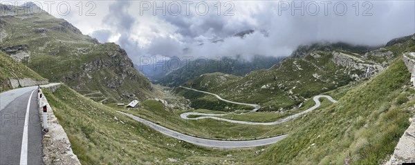 Panoramic photo of winding pass road to Alpine pass Colle del Col de Nivolet, low-hanging clouds in the background, Gran Paradiso National Park, Ceresole Reale, Piedmont, Italy, Europe