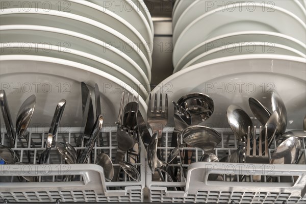 Dishwasher, full, with cleaned crockery, cutlery, cooking utensils