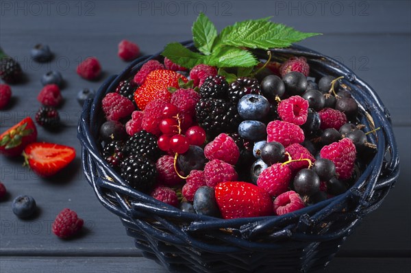 Mix of fresh berries, in a basket, on a wooden gray table, no people, top view