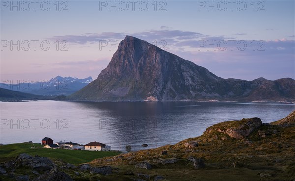 Landscape at Stornappstinden mountain. View of the mountain Offersoykammen on Vestvagoya. Some houses in the foreground. At night at the time of the midnight sun in good weather. Early summer. Flakstadoya, Lofoten, Norway, Europe