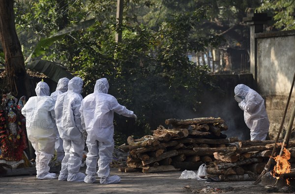 Family members wearing PPE kit performing last rites of a person who died of COVID-19 coronavirus disease, at a cremation ground in Guwahati, Assam, India on Saturday, January 29, 2022. India registered 250 thousand new coronavirus cases including Coronavirus Omicron Cases, in the last 24 hours, while 573 people died due to the infection