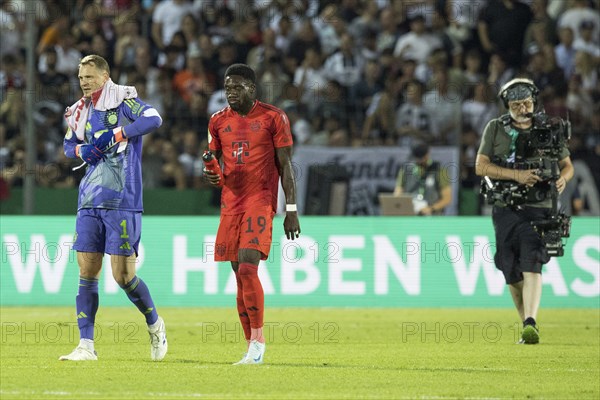 Football match, captain and goalkeeper Manuel NEUER FC Bayern Munich left, takes off his gloves after the match, next to him his team mate Alphonso Boyle DAVIES FC Bayern Munich, both under the eyes of a cameraman, football stadium Donaustadion, Ulm, Germany, Europe