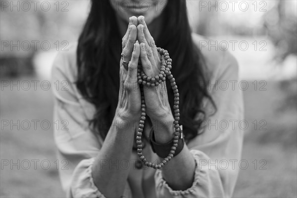 A mindful woman is holding hands in a namaste position while practicing breathing outdoors