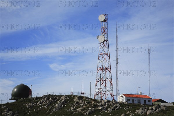 Antenna station, here in the Algarve, Portugal, radio tower and radar facilities on a rocky hill with a small building and blue sky in the background, Europe