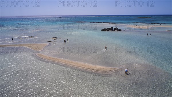 Sandbank in clear, calm sea with scattered people enjoying the natural surroundings, Elafonissi, lagoon, south-west tip of Crete, Crete, Greek Islands, Greece, Europe